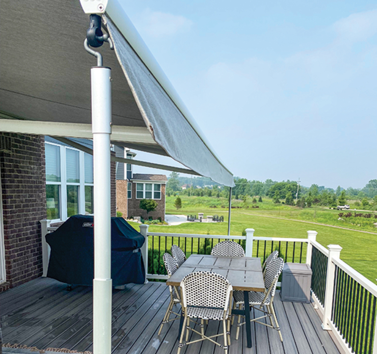 Backyard deck with awning and outdoor furniture.