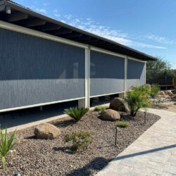 Outdoor patio with sun shade and desert landscaping.